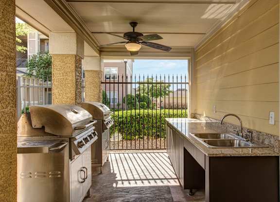A patio with a sink and grill is covered by a roof.