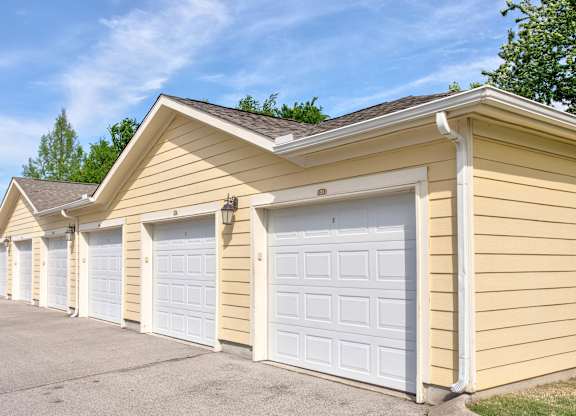 A series of garages with white doors are lined up in a row.