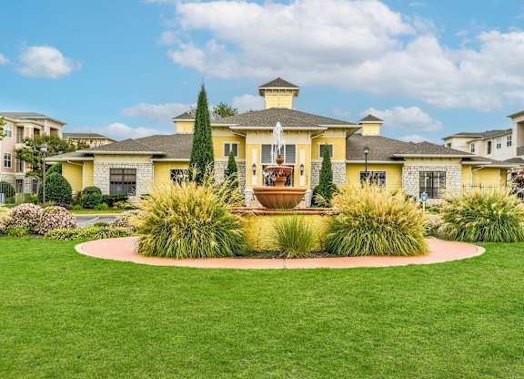 A yellow house with a fountain in the front yard.