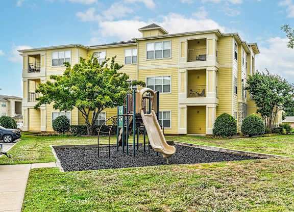 A yellow apartment building with a playground in front.