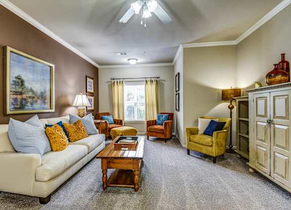 A living room with a white couch, a yellow chair, and a painting on the wall.