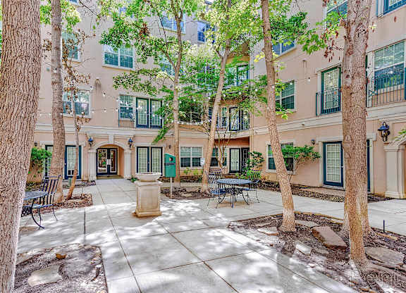 A courtyard with a bench and a tree in front of a building.