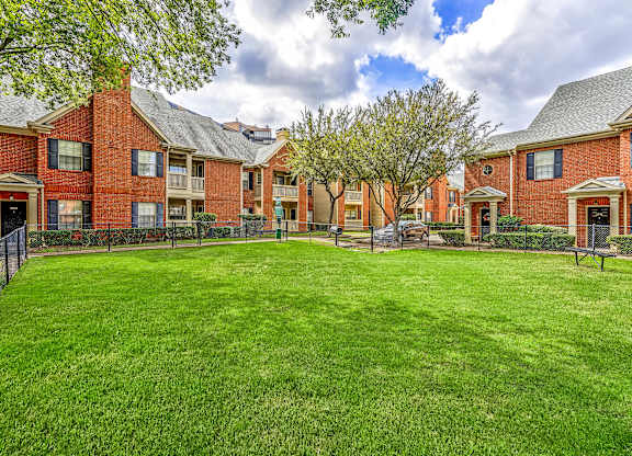 A large grassy area in front of a row of red brick houses.