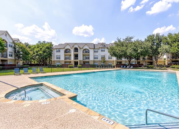 A large swimming pool in front of apartment buildings.