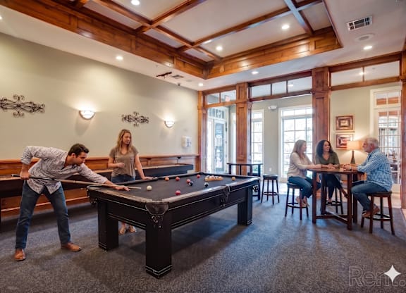 A man is playing pool in a room with a pool table.