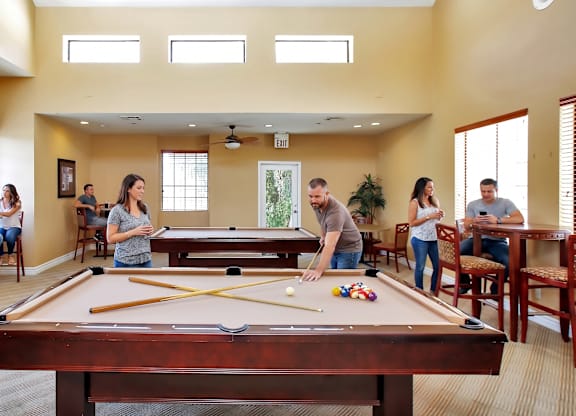 A group of people playing pool in a room.