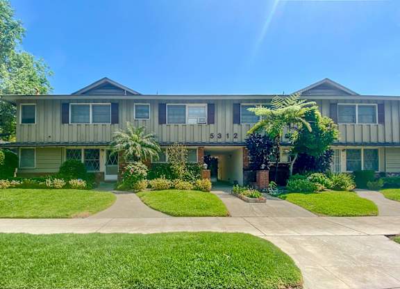 A sunny day at a residential building with a green lawn in front.
