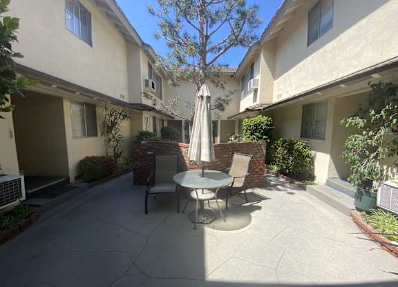 A patio with a table and chairs and an umbrella.
