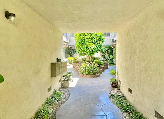 A pathway leads through a courtyard with a variety of plants.