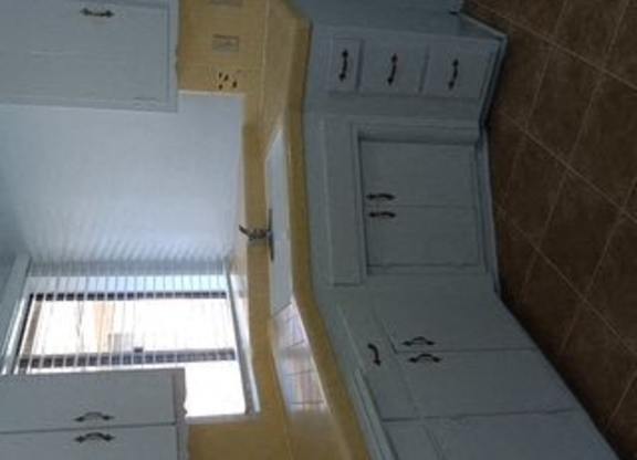 A white cabinet with drawers and a yellow cabinet with drawers are in a room.