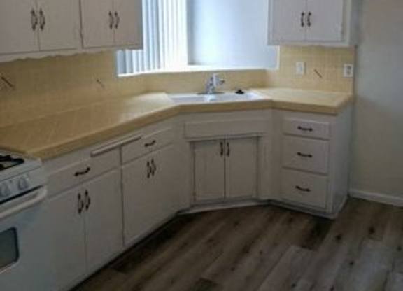 A kitchen with white cabinets and a counter top.