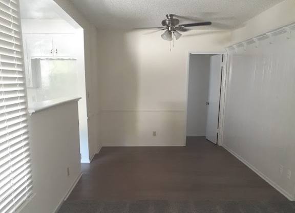 A room with a ceiling fan and carpeted floor.