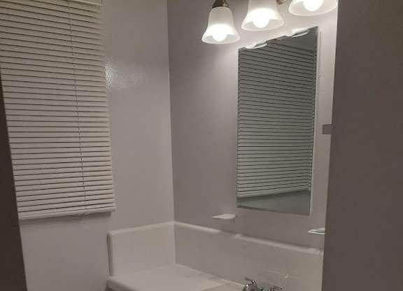 A white bathroom with a sink and mirror.