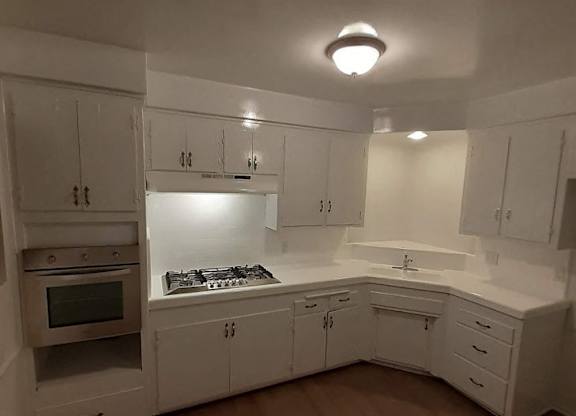 A kitchen with white cabinets and a stove top oven.