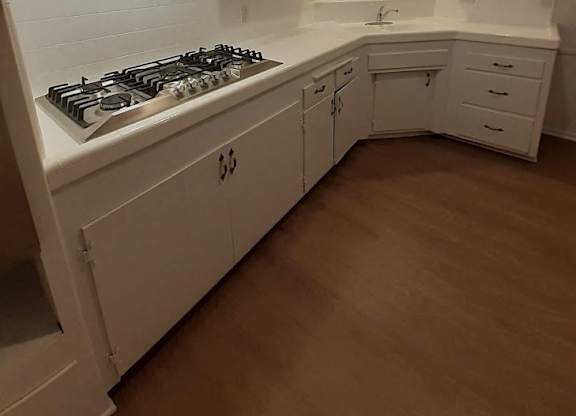 A kitchen with white cabinets and a stove top oven.