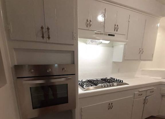 A white kitchen with a stove top oven and microwave.