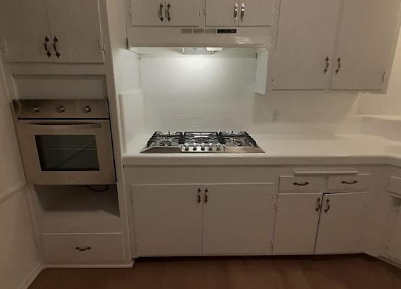A kitchen with white cabinets and a stove top oven.