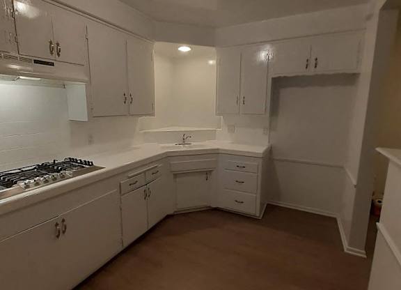 A kitchen with white cabinets and a stove top oven.