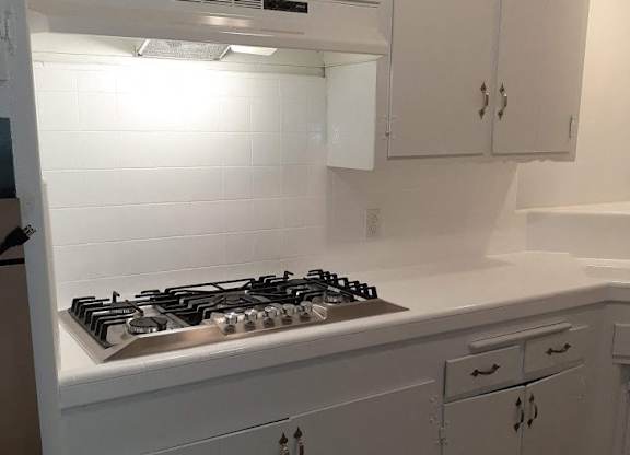 A white kitchen with a stove top oven.