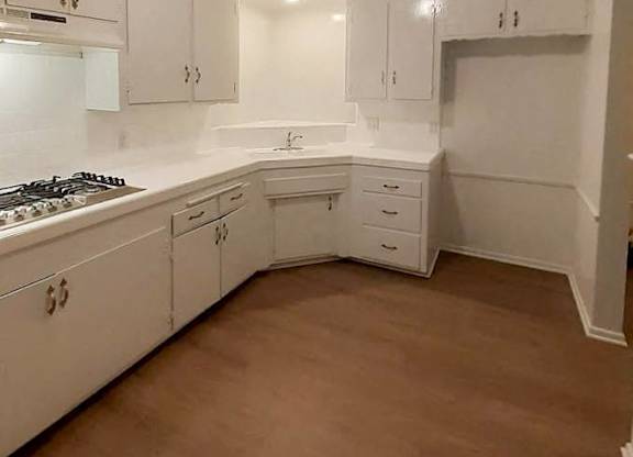 A kitchen with white cabinets and a wooden floor.