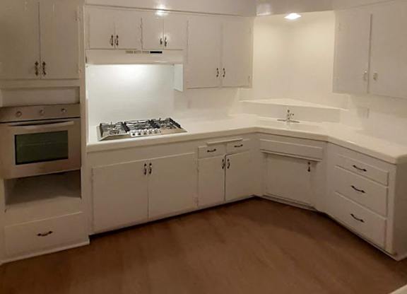 A kitchen with white cabinets and a stove top oven.