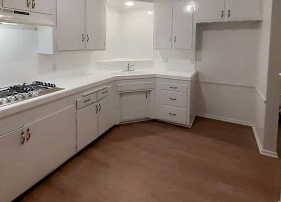 A kitchen with white cabinets and a brown floor.