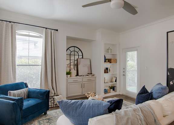 Living room with blue furniture and built in shelving at Silverado Apartments, Frisco