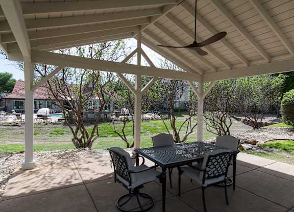 Covered outdoor with dining furniture and ceiling fan at Silverado Apartments, Texas