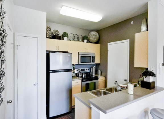 Kitchens with storage cabinets at Mission at La Villita Apartments in Irving, TX offers 1, 2 & 3 bedroom apartment homes with appliances.