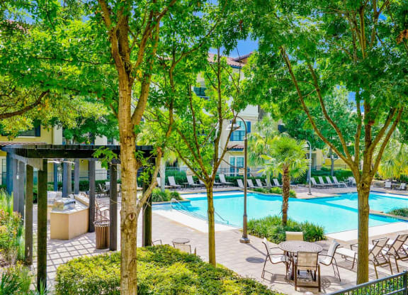 Sparkling pool surrounded by trees at Mission at La Villita Apartments in Irving, TX offers 1, 2 & 3 bedroom apartment homes with appliances.