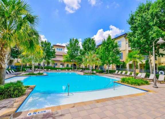 Sparkling pool with lounge chairs at Mission at La Villita Apartments in Irving, TX offers 1, 2 & 3 bedroom apartment homes with appliances.