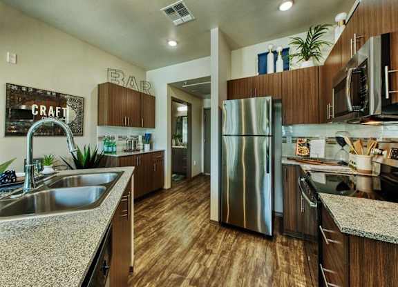 kitchen with stainless steel double sink and stainless steel refrigerator.  Beautiful modern cabinets line kitchen walls and surround black range. at Craft at Gilbert and Baseline Apartments, Arizona,