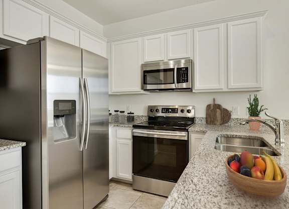 A kitchen with a stainless steel refrigerator, oven, and microwave.