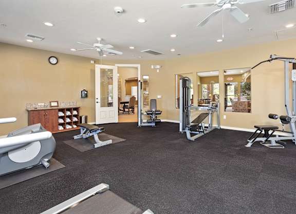 A spacious gym with a variety of equipment including a treadmill, weights, and a bench press. at Superstition Canyon Apartments, Mesa