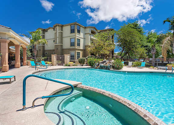 A swimming pool in front of a building with a blue sky in the background. at Superstition Canyon Apartments, Mesa, Arizona
