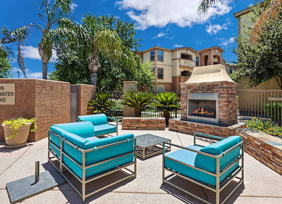 A patio with a fireplace and two chairs. at Superstition Canyon Apartments, Apartments, Mesa, AZ