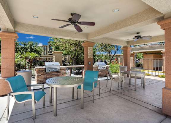 A patio with a table and chairs under a roof. at Superstition Canyon Apartments, Apartments, Mesa, AZ