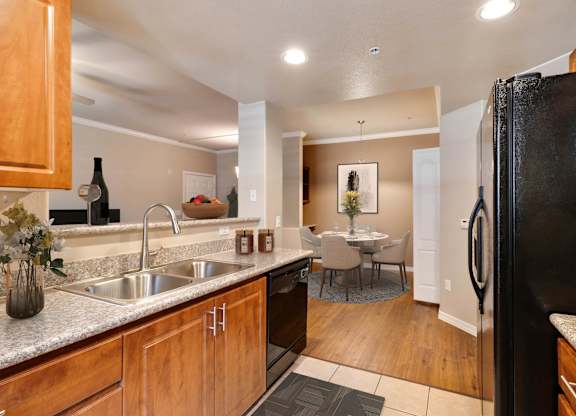 A kitchen with a black refrigerator and wooden cabinets. at Superstition Canyon Apartments, Mesa, Arizona
