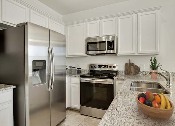 A kitchen with a stainless steel refrigerator, oven, and microwave.