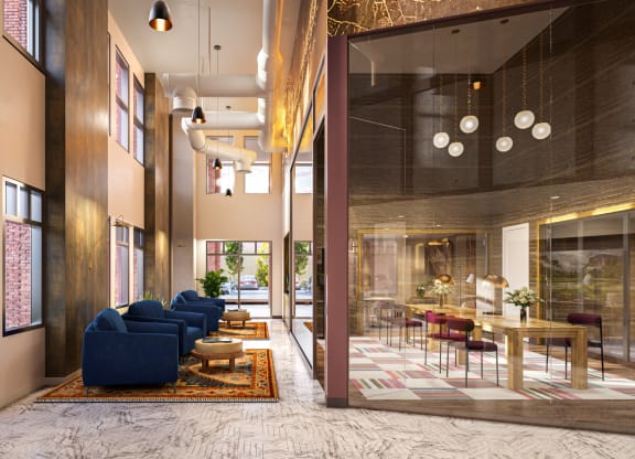 a lobby with blue couches and a table with chairs and a large glass door at Link Apartments® Broad Ave, Tennessee