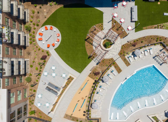 Beautiful drone shot of courtyard with pool, grills, and firepit at Link Apartments® Linden in Chapel Hill