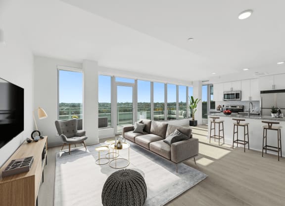 an open living room with a couch and a chair and a kitchen with a counter