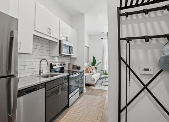 an apartment kitchen with stainless steel appliances and white cabinets