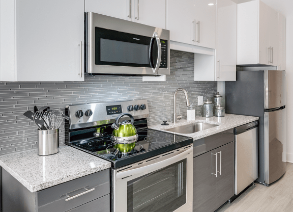 a kitchen with stainless steel appliances and white cabinets  at Link Apartments® Mixson, South Carolina