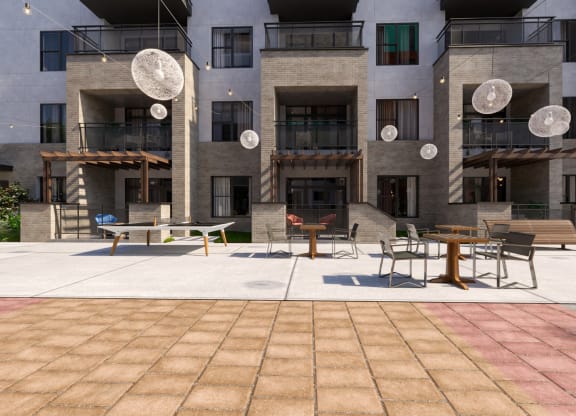 a courtyard with tables and chairs in front of an apartment building