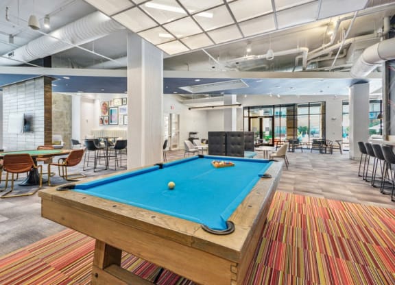 a pool table in a lobby with tables and chairs at Link Apartments Innovation Quarter, Winston Salem, NC