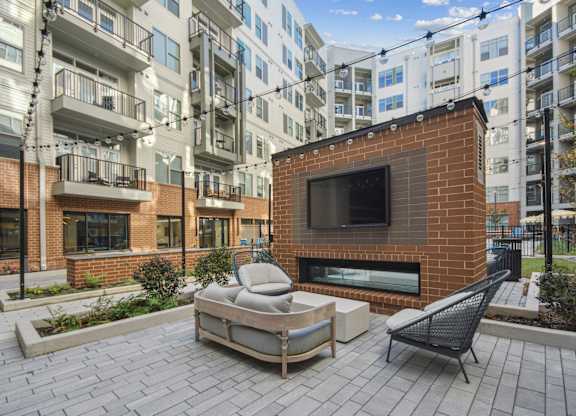 an outdoor patio with a fireplace and a couch and a chair at Link Apartments® Calyx, Chapel Hill, 27517