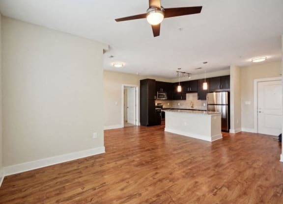 an empty living room and kitchen with a ceiling fan at Link Apartments® Brookstown, Winston Salem, NC