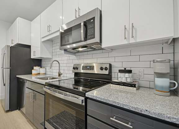 a modern kitchen with stainless steel appliances and granite counter tops at Link Apartments® Calyx, North Carolina, 27517