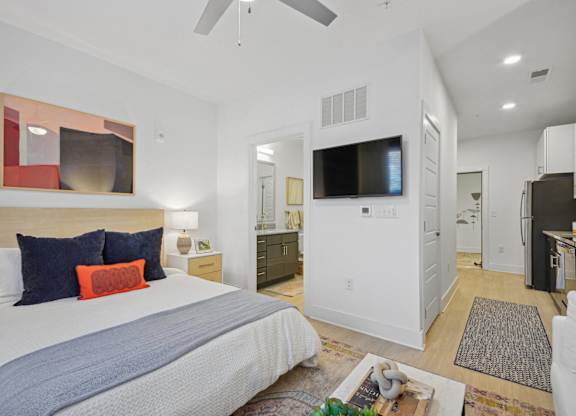 a bedroom with a bed and a tv in a white room at Link Apartments® Calyx, Chapel Hill, NC 27517